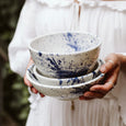 Person holding hand-painted white and blue bowls