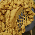 Close up of a tumeric-coloured wool blanket on a leather stool