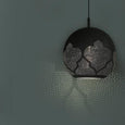 Black patterned pendant light on a teal background