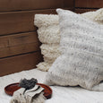 Wooden bench with two textured pillows, blanket, and wooden tray