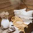 Wooden bench with textured pillows, blankets, and vase