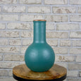 Teal cylinder vase with copper accents on a wooden stool