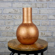 Marble and copper cylinder vase on a wooden stool 