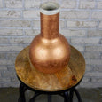 Marble and copper cylinder vase on a wooden stool 